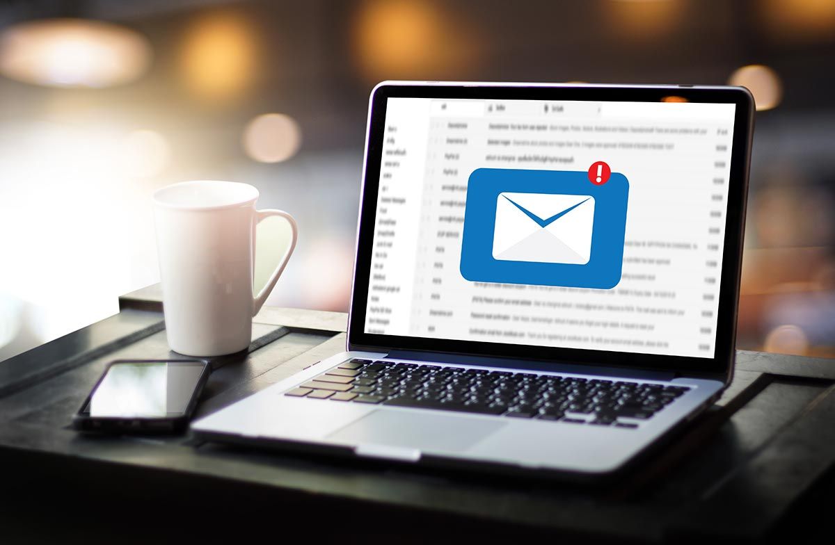 Laptop im Maileingang Eingeschalteter Laptop, großes E-Mail Zeichen auf Desktop