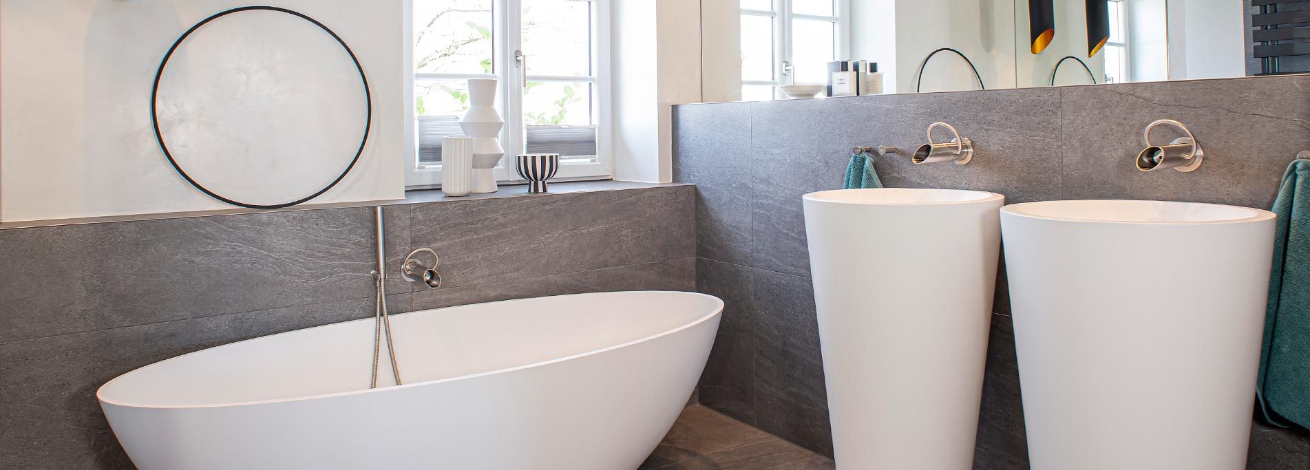 Foto einer modernen Badewanne mit freistehenden Waschbecken und dunklen Natursteinfliesen.