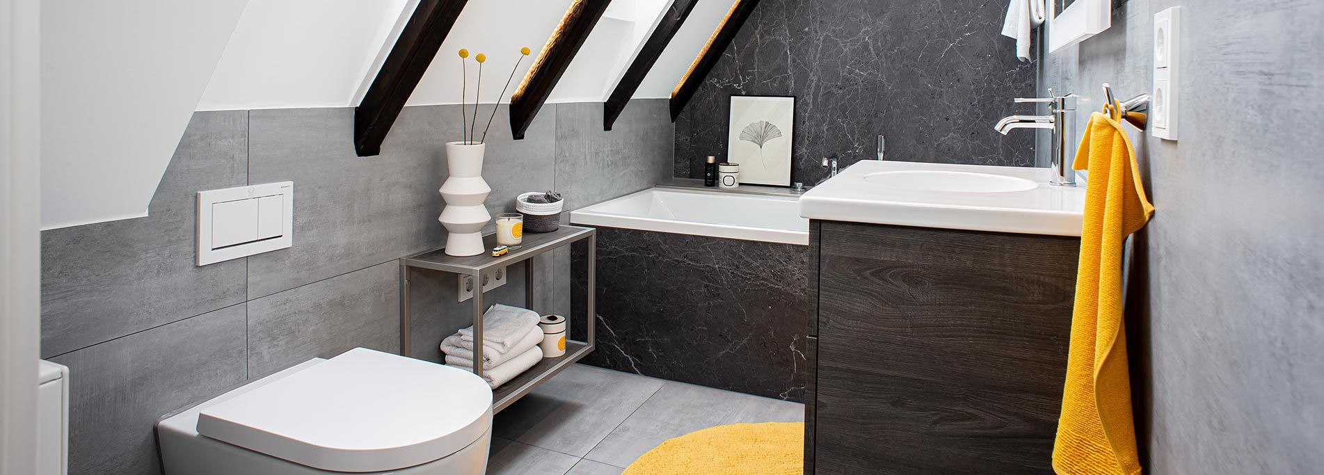 Badezimmer mit Dachschräge, Badewanne mit schwarzer Marmorverkleidung, Waschtisch in dunkler Holzoptik 